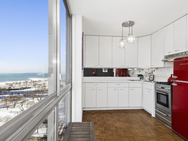 kitchen with decorative light fixtures, dark parquet flooring, stainless steel range with gas stovetop, white cabinetry, and a water view