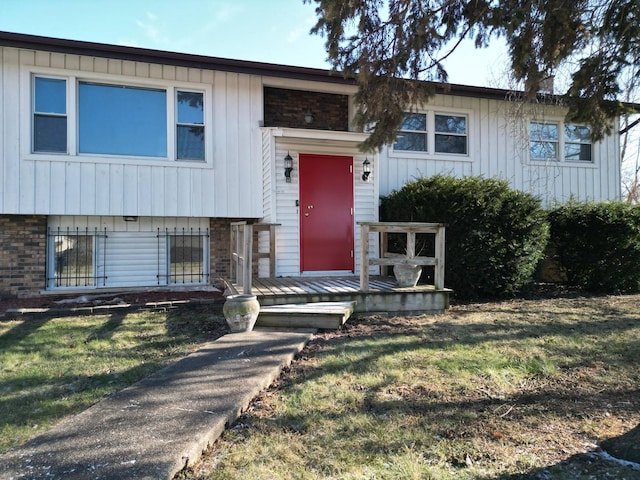 split foyer home featuring brick siding, board and batten siding, and a front yard