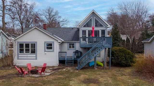 back of property featuring a lawn, a wooden deck, and a fire pit