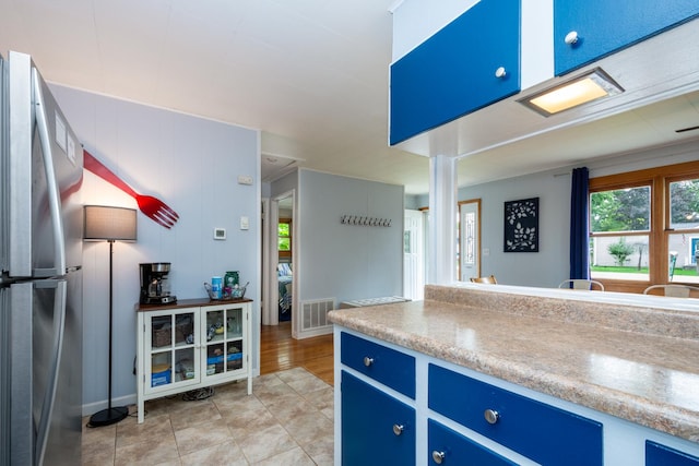 kitchen with stainless steel refrigerator and blue cabinets