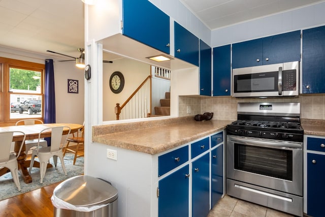 kitchen with ceiling fan, blue cabinets, light hardwood / wood-style floors, decorative backsplash, and appliances with stainless steel finishes