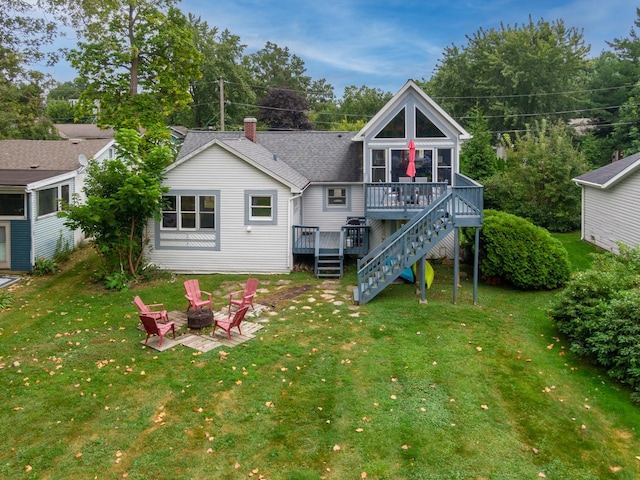 back of property featuring a fire pit, a patio area, a yard, and a wooden deck