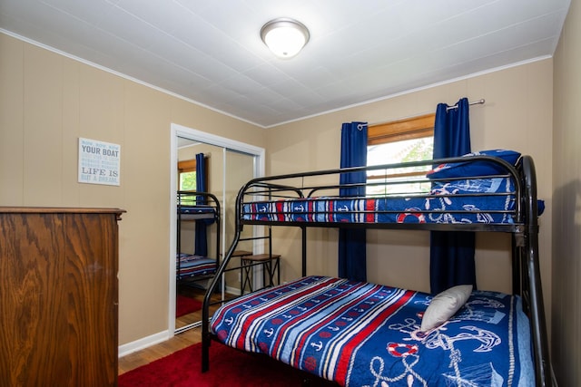 bedroom with a closet, wood-type flooring, and ornamental molding