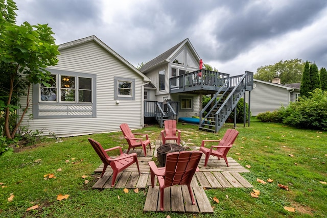 rear view of property with a deck, an outdoor fire pit, and a lawn