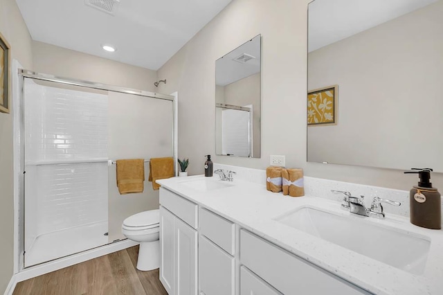 bathroom featuring wood-type flooring, toilet, an enclosed shower, and vanity