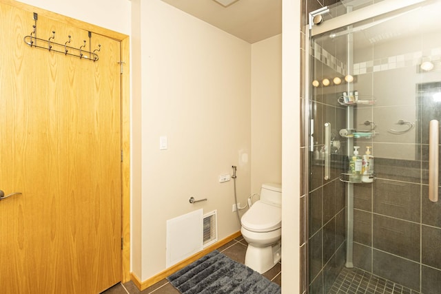 bathroom featuring tile patterned floors, toilet, and a shower with door