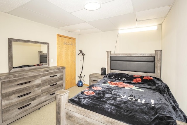 carpeted bedroom featuring a drop ceiling