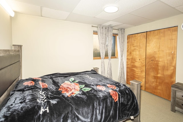 bedroom featuring carpet, a drop ceiling, and a closet