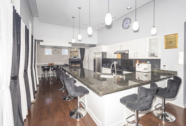 kitchen featuring white cabinets, decorative light fixtures, stainless steel appliances, sink, and a breakfast bar