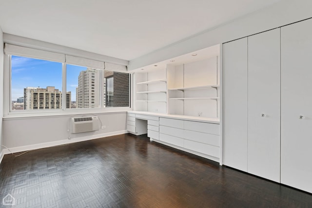 unfurnished office featuring built in desk and a wall mounted air conditioner