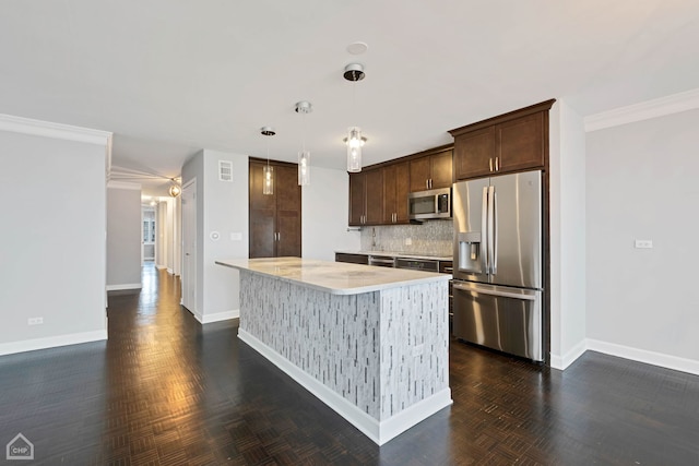 kitchen with pendant lighting, decorative backsplash, appliances with stainless steel finishes, dark brown cabinets, and a kitchen island