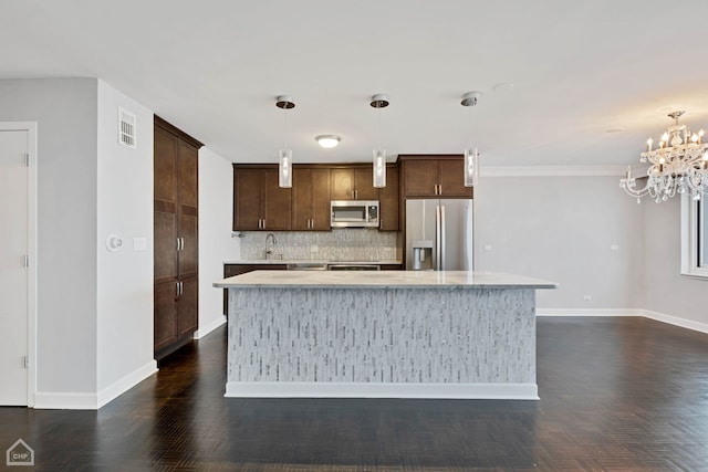 kitchen with backsplash, an inviting chandelier, appliances with stainless steel finishes, decorative light fixtures, and a kitchen island