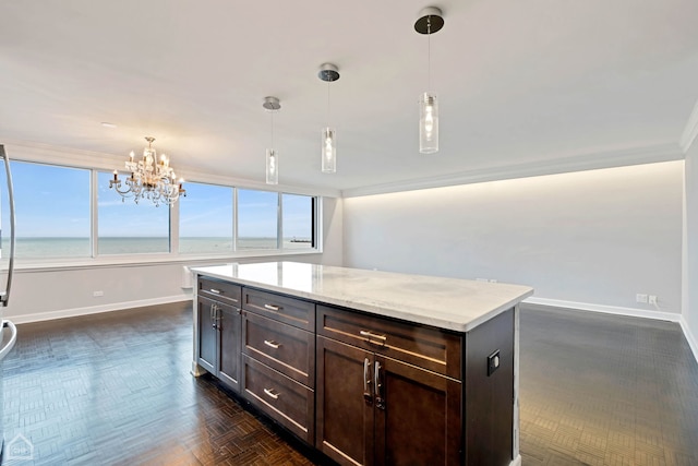 kitchen with light stone countertops, decorative light fixtures, a water view, and ornamental molding