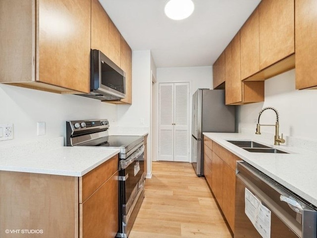 kitchen with sink, stainless steel appliances, and light wood-type flooring