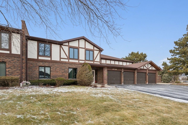 tudor house featuring a garage and a front lawn