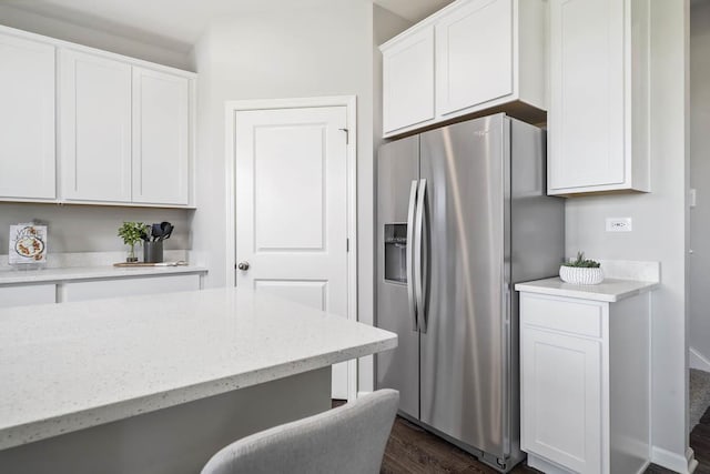 kitchen with white cabinetry, a breakfast bar, dark wood-type flooring, and stainless steel refrigerator with ice dispenser