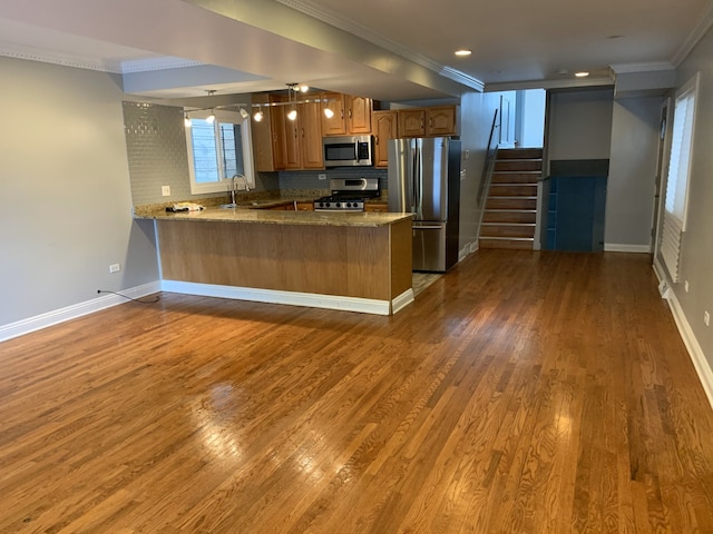 kitchen featuring kitchen peninsula, tasteful backsplash, ornamental molding, stainless steel appliances, and dark wood-type flooring