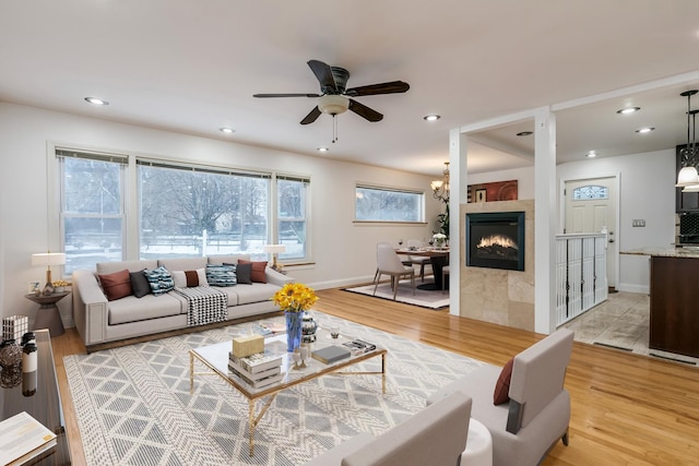 living room featuring ceiling fan, light hardwood / wood-style floors, and a tiled fireplace