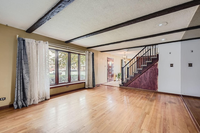 unfurnished room featuring beamed ceiling, wood-type flooring, a textured ceiling, and an inviting chandelier