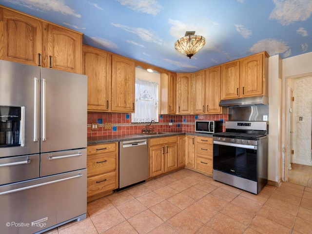 kitchen with tasteful backsplash, sink, light tile patterned flooring, stainless steel appliances, and dark stone counters