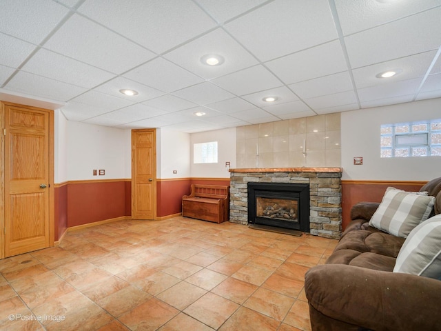 living room featuring a paneled ceiling, a fireplace, and wooden walls