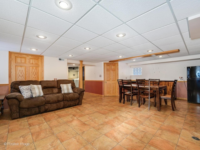 living room with a drop ceiling and wooden walls