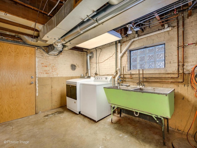 washroom featuring washer and clothes dryer, sink, and brick wall