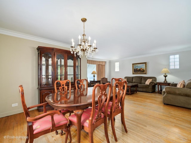 dining space with light hardwood / wood-style flooring, ornamental molding, and a healthy amount of sunlight