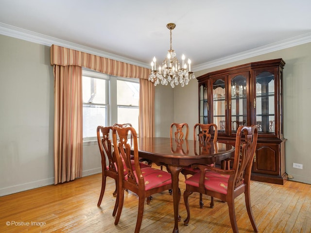 dining space featuring ornamental molding, a chandelier, and light hardwood / wood-style flooring