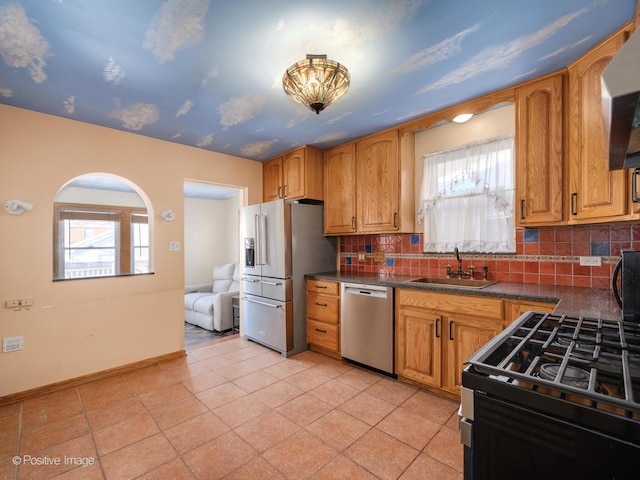 kitchen featuring a wealth of natural light, stainless steel appliances, sink, backsplash, and light tile patterned floors