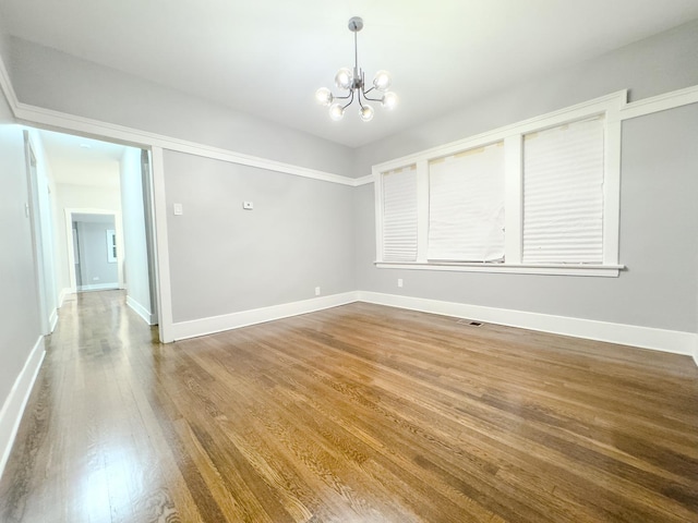 spare room featuring hardwood / wood-style flooring and a notable chandelier