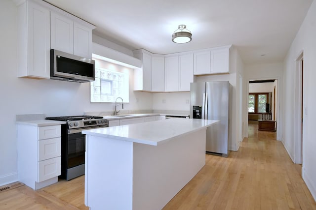 kitchen featuring a center island, sink, stainless steel appliances, light hardwood / wood-style floors, and white cabinets