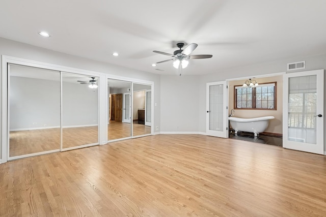 unfurnished bedroom with multiple closets, light wood-type flooring, visible vents, and baseboards