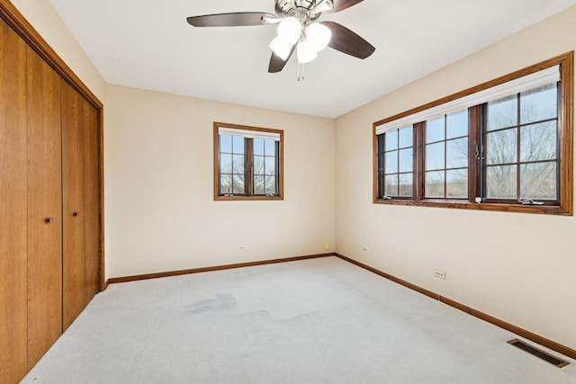 unfurnished bedroom with a closet, visible vents, light carpet, and baseboards