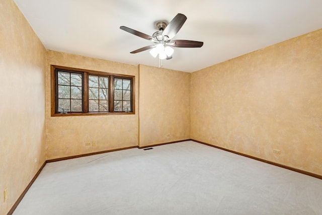 empty room featuring a ceiling fan, light colored carpet, visible vents, and baseboards