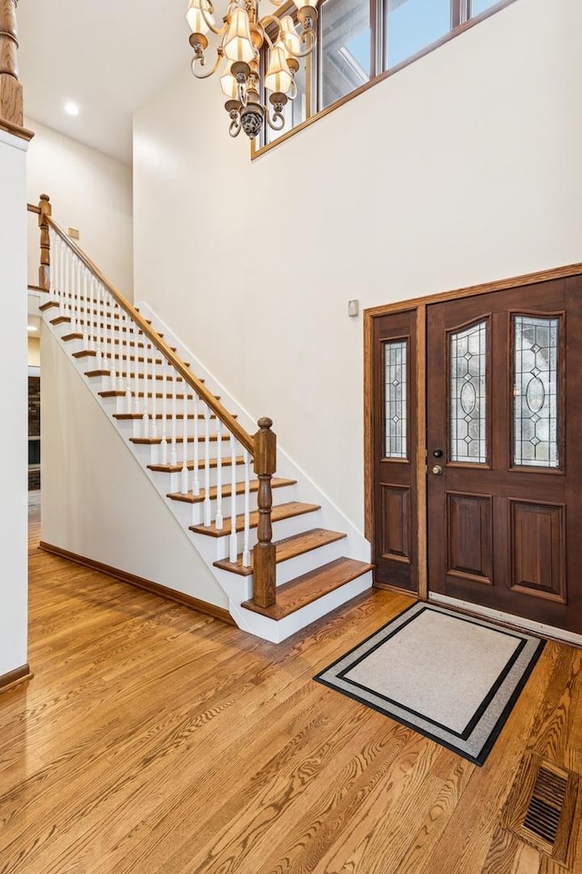 entrance foyer featuring stairs, visible vents, a high ceiling, and wood finished floors