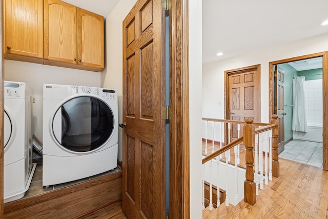 laundry room with cabinet space, recessed lighting, light wood-style floors, and washing machine and clothes dryer