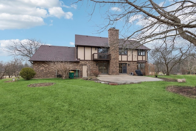 rear view of property featuring a patio, a chimney, a balcony, and a lawn