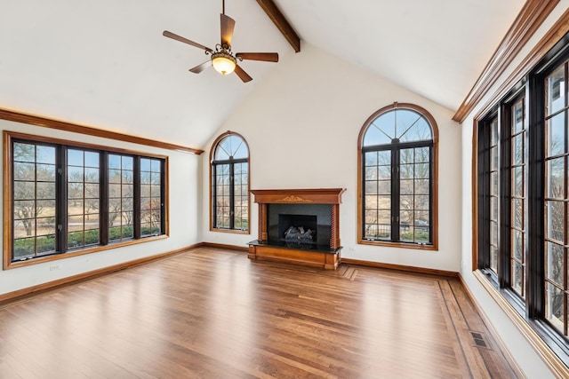 unfurnished living room featuring beam ceiling, a fireplace with raised hearth, wood finished floors, high vaulted ceiling, and baseboards