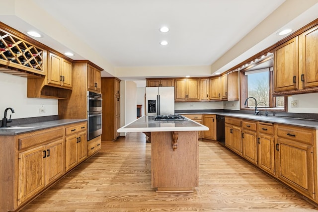 kitchen featuring a center island, stainless steel appliances, light wood-style floors, a sink, and a kitchen breakfast bar