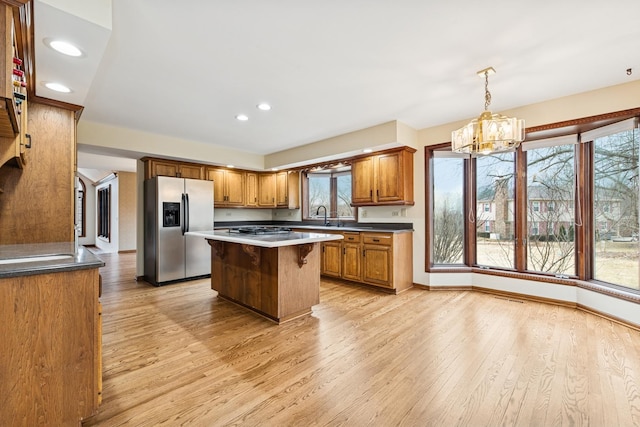 kitchen with light wood-type flooring, brown cabinetry, stainless steel appliances, and a center island