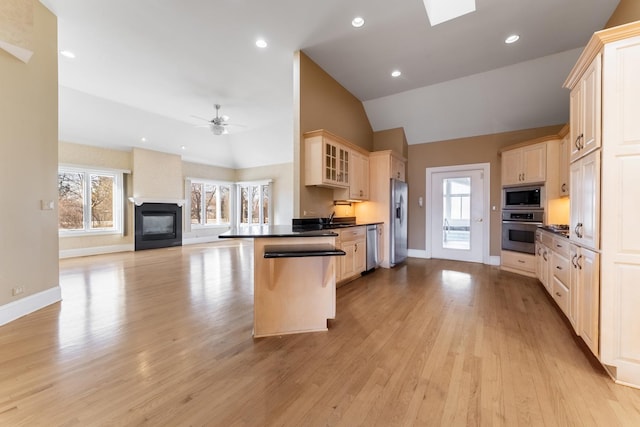 kitchen featuring appliances with stainless steel finishes, vaulted ceiling with skylight, a breakfast bar, ceiling fan, and plenty of natural light