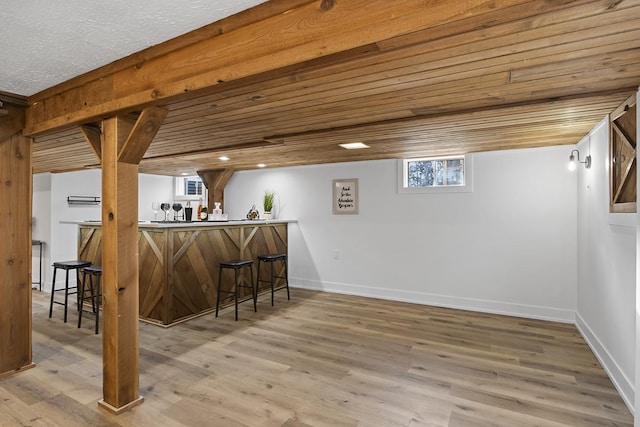 bar featuring a healthy amount of sunlight, wood ceiling, and light hardwood / wood-style flooring