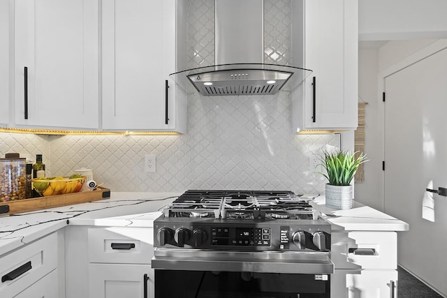 kitchen with white cabinetry, high end range, light stone countertops, and wall chimney range hood