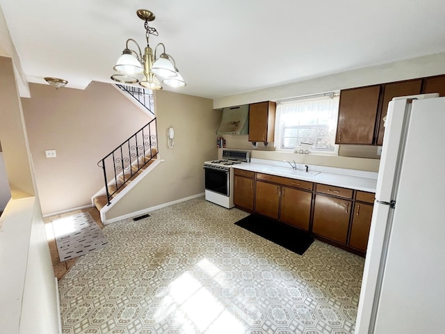 kitchen with dark brown cabinetry, sink, hanging light fixtures, white appliances, and wall chimney range hood