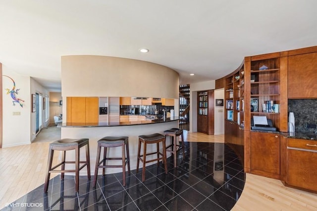 kitchen featuring stainless steel fridge with ice dispenser, decorative backsplash, wood-type flooring, and a breakfast bar