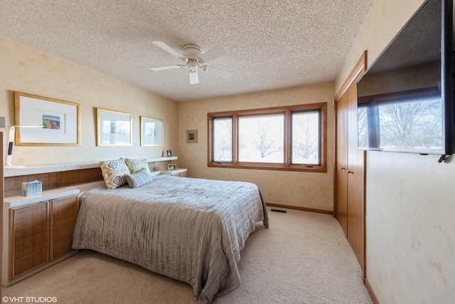 bedroom featuring ceiling fan, light colored carpet, and a textured ceiling