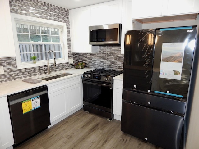 kitchen featuring white cabinetry, sink, dark wood-type flooring, tasteful backsplash, and black appliances