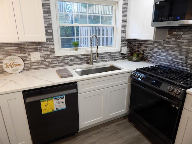 kitchen with light stone countertops, white cabinetry, sink, backsplash, and black appliances