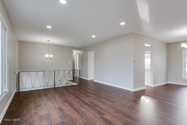 empty room with a chandelier and dark hardwood / wood-style flooring